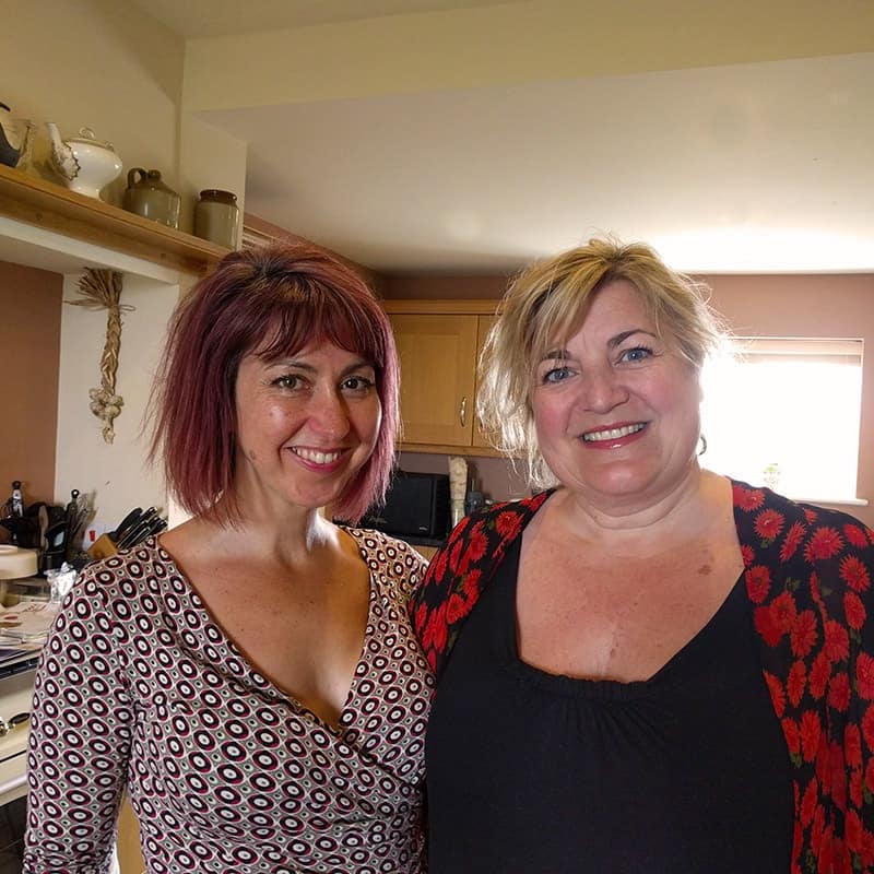 Warm women smiling in a cozy kitchen setting, enjoying a friendly moment together.
