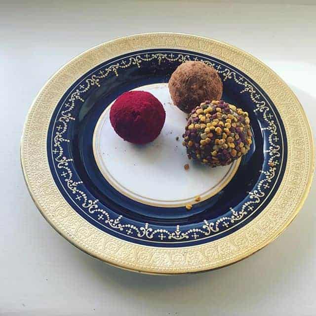 Elegant dessert truffles on a decorative gold and navy plate, showcasing gourmet confectionery with vibrant colors and textures.