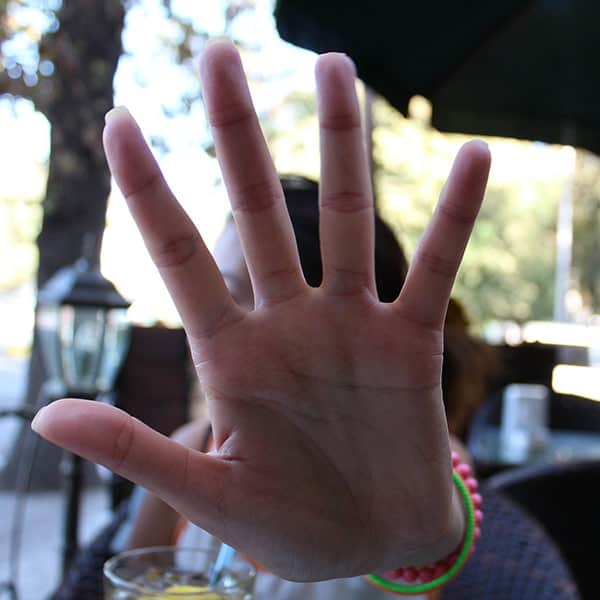 Hand Blocking Camera at Outdoor Cafe