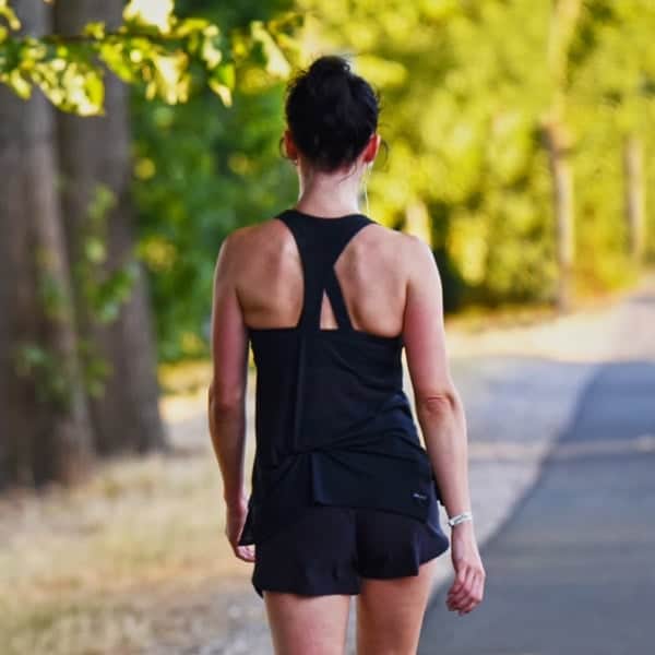 Running woman in athletic wear on a scenic trail during daytime.