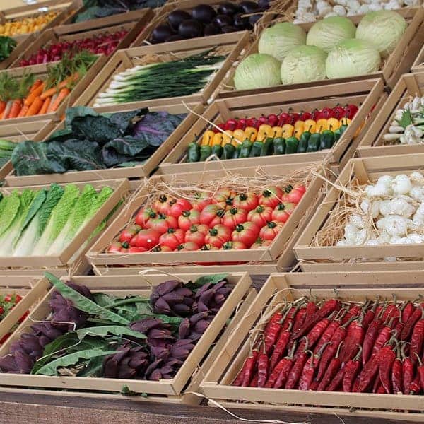Fresh organic vegetables and herbs displayed in wooden crates at Raw Horizons market.