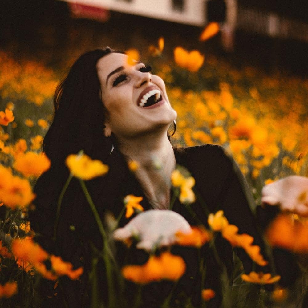 Joyful woman in a field of orange flowers, smiling and enjoying nature.