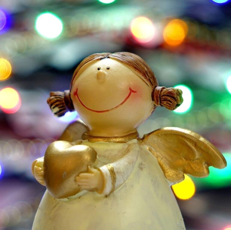 Angel figurine holding a heart with colorful blurred lights in the background.
