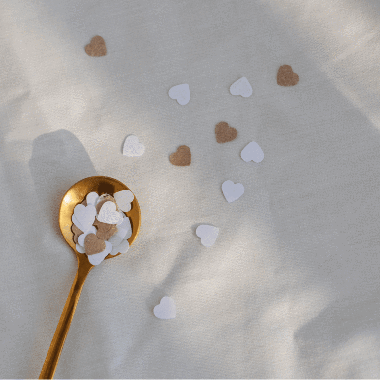 Heart Confetti on White Surface with Gold Spoon