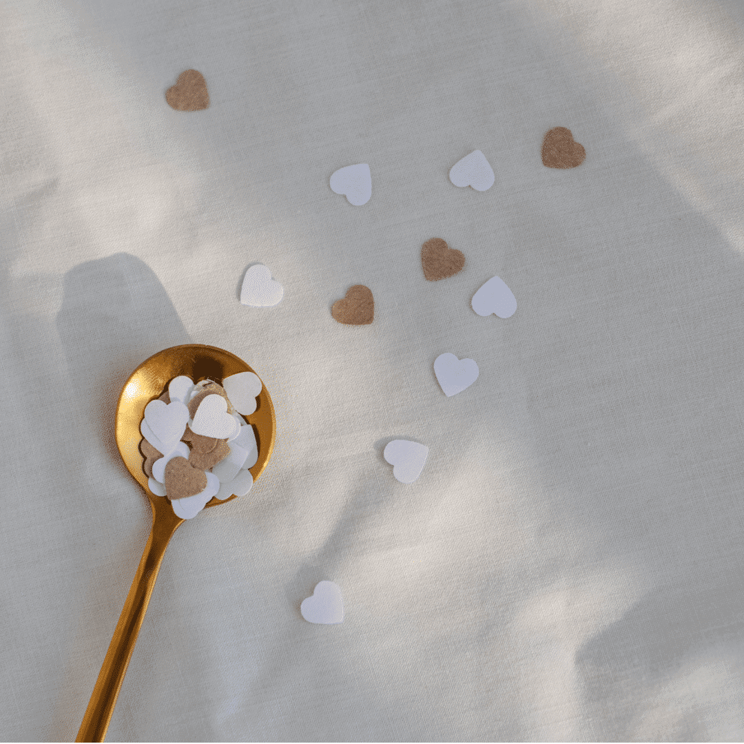 Heart Confetti on White Surface with Gold Spoon