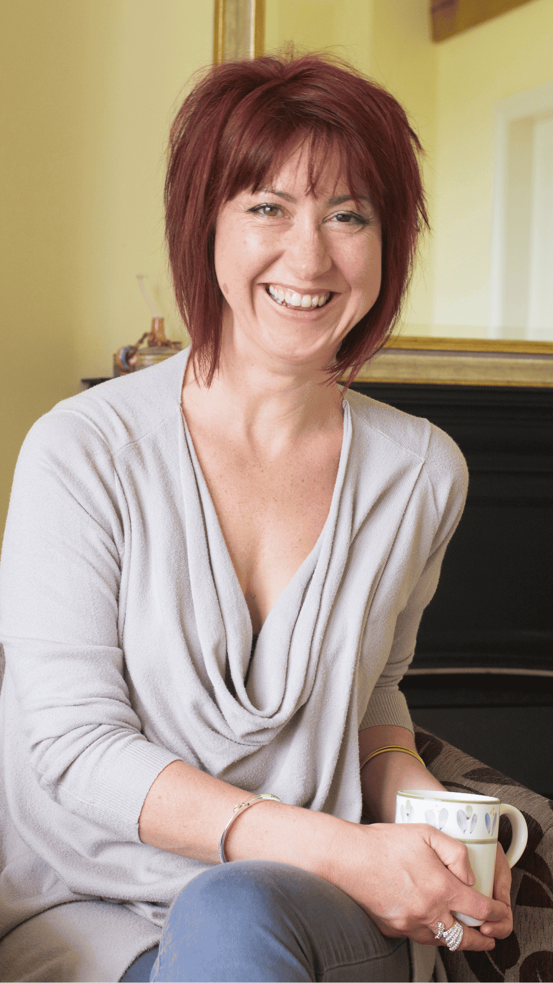 Wellbeing coach smiling with coffee in a cozy home setting.