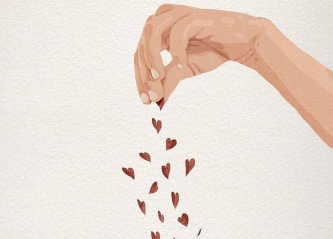 Hand dropping small heart-shaped confetti, symbolizing love and affection.