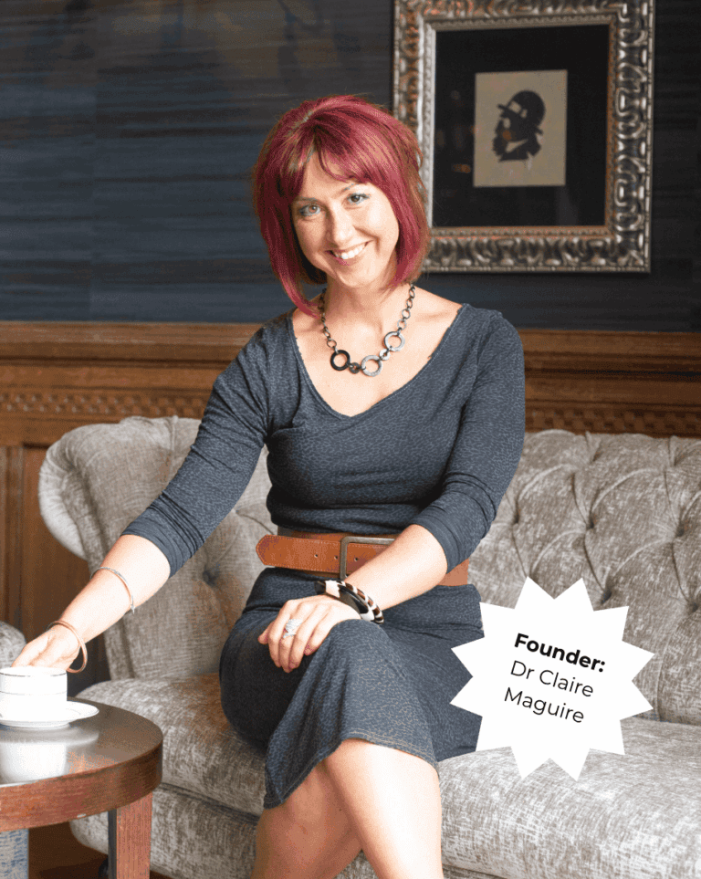 Portrait of Dr. Claire Maguire, founder of Raw Horizons, sitting on a sofa in a cozy setting.