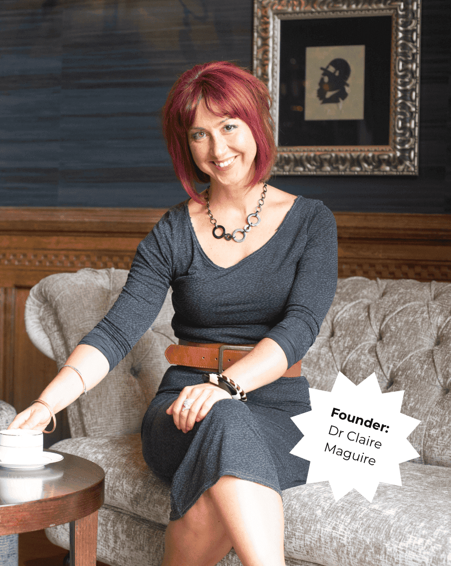 Portrait of Dr. Claire Maguire, founder of Raw Horizons, sitting on a sofa in a cozy setting.